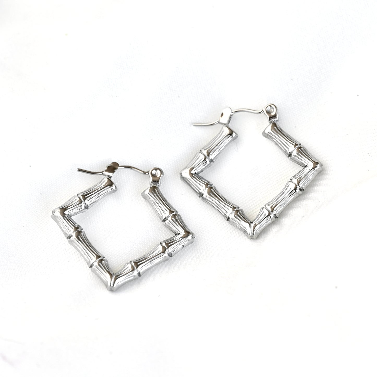 A pair of geometric silver hoop earrings designed to look like segmented bamboo stalks, shown on a plain white background.