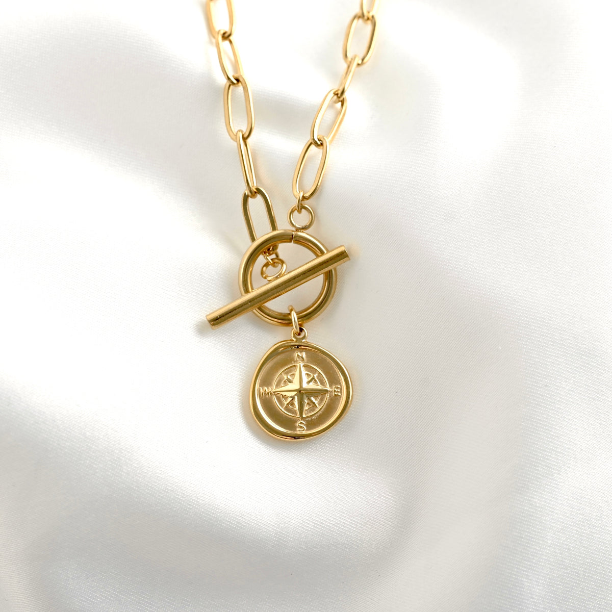 Gold necklace with a compass pendant on a white background