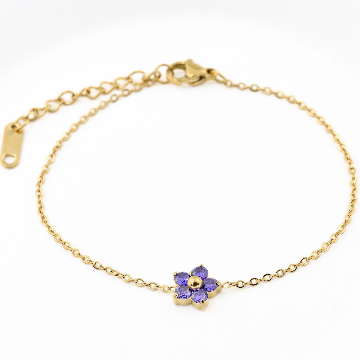 Gold bracelet with a purple flower charm on a white background