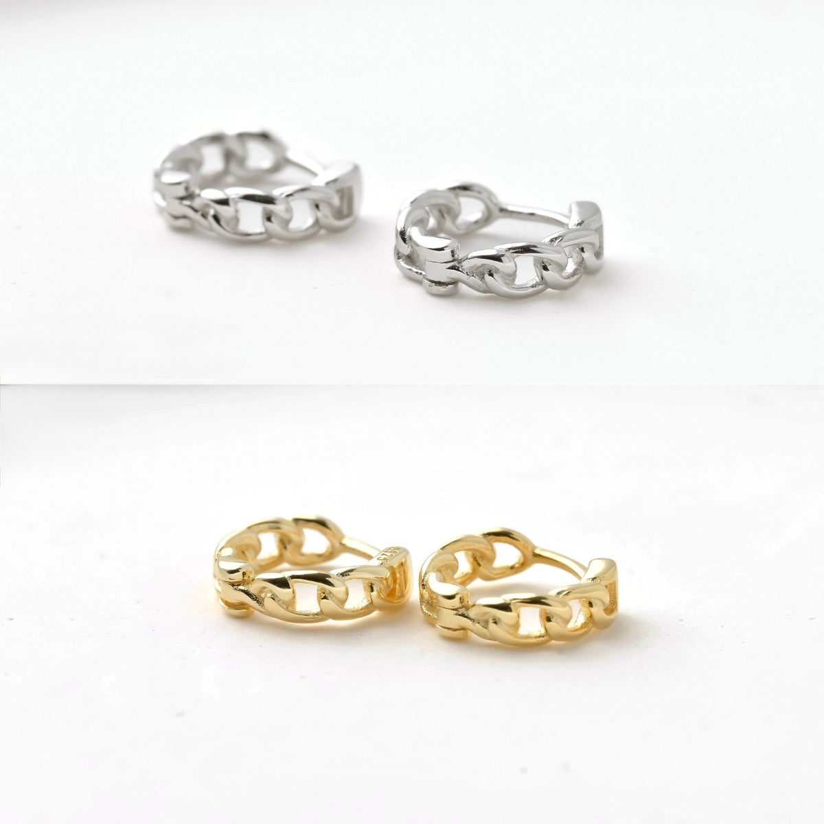 Pair of small gold and silver curb chain hoop earrings on a white background