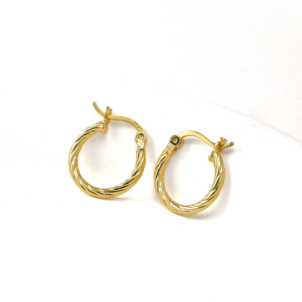 Mini gold hoop earrings with S925 stamp on latch back clasp on a white background