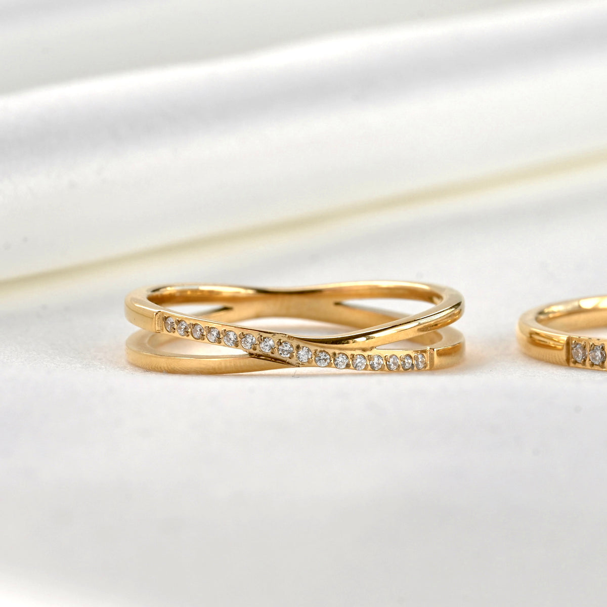 Close-up view of slim X ring with one band pave set with CZ stones while the other is smooth and polished.
