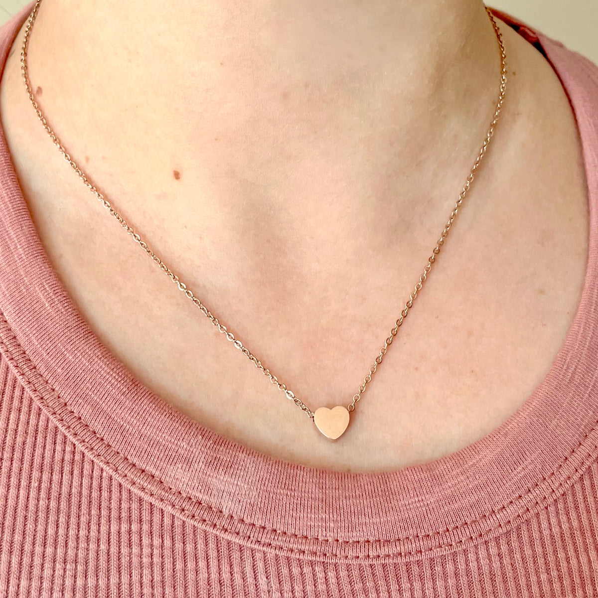 Rose gold necklace with a heart pendant on a pink top