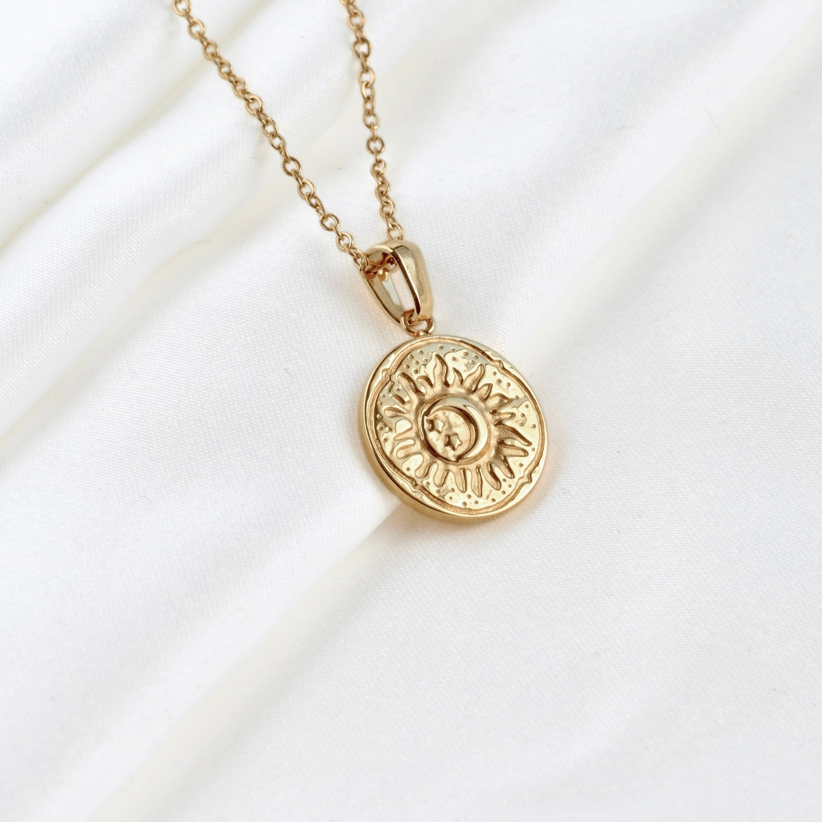 Gold necklace with an antiqued sun pendant on a white background