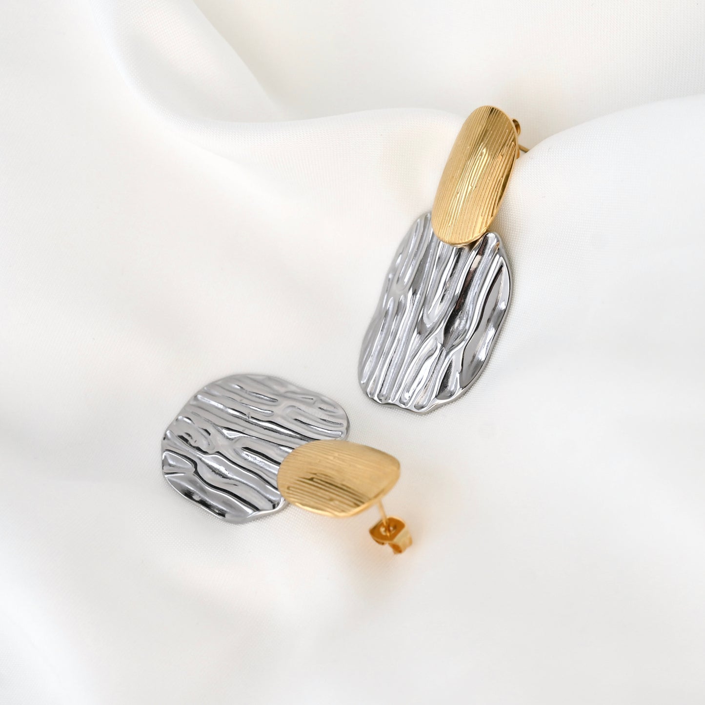 Pair of earrings with gold and silver designs on a white background