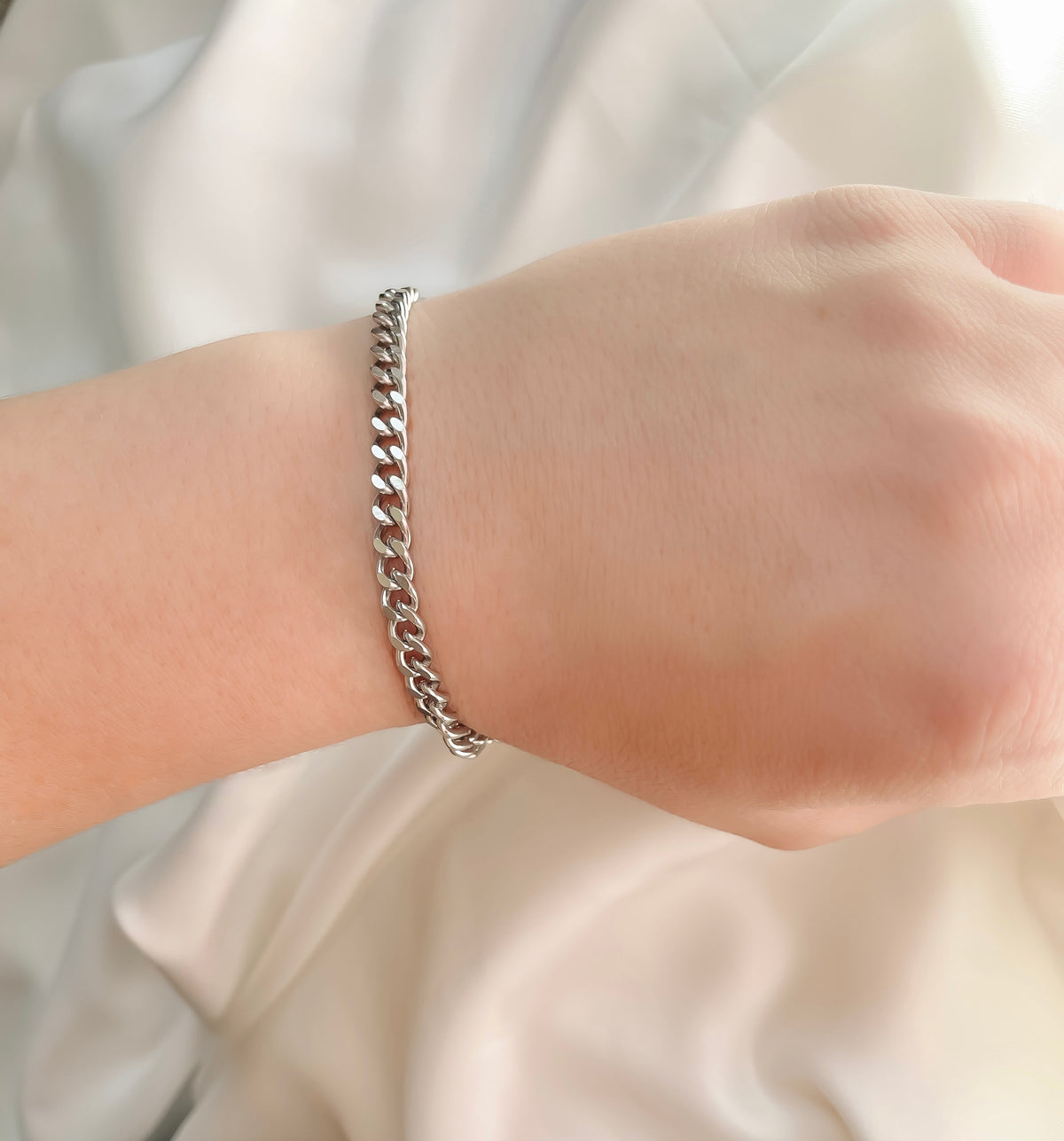5mm silver cuban chain bracelet on a wrist with a neutral background