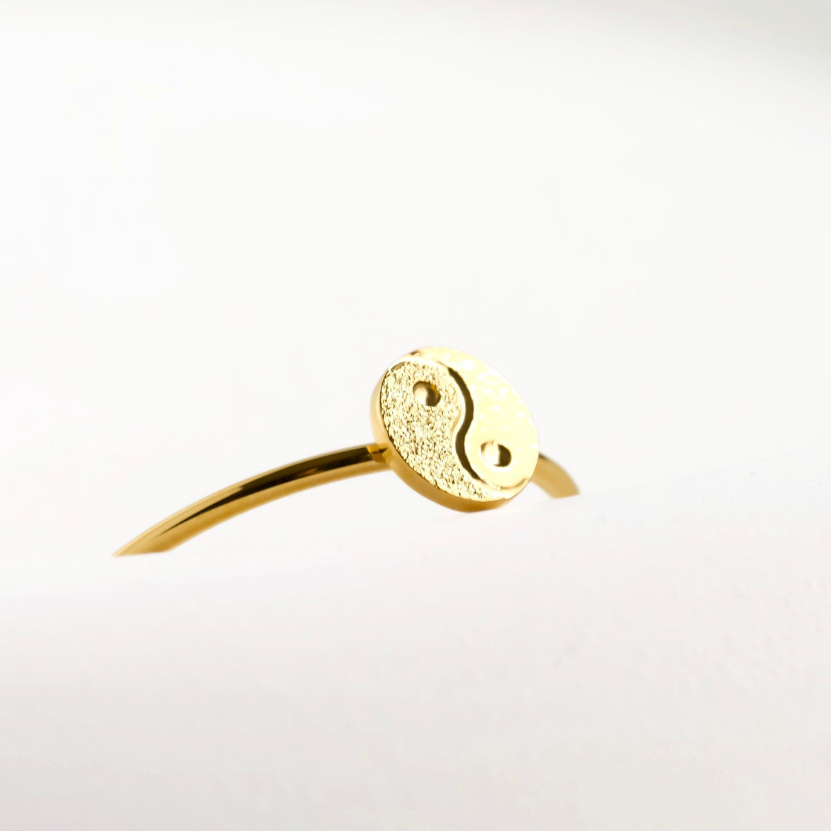 Close-up view of the yin and yang charm on the ring on a light gray background