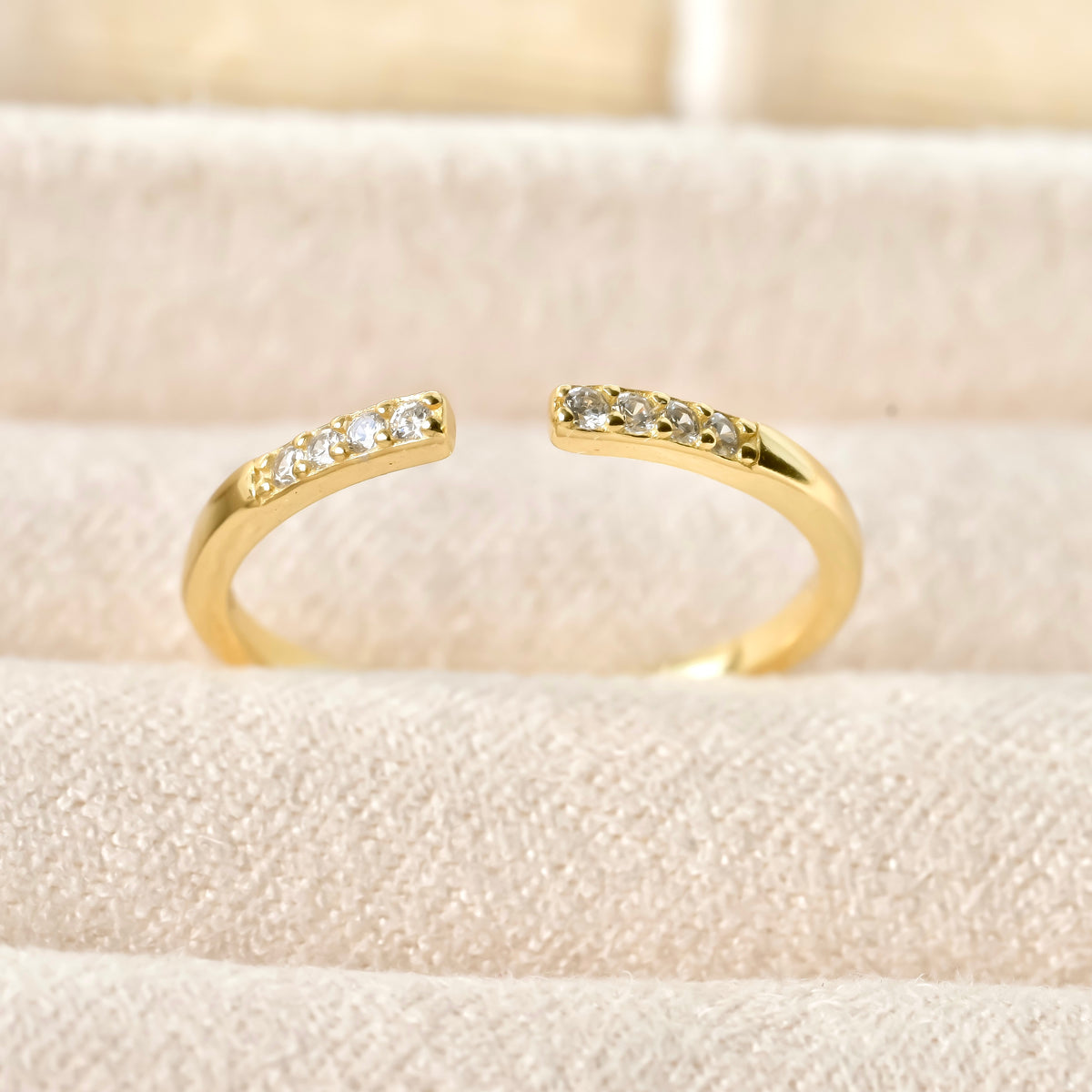 Super dainty adjustable pave diamond gold pinky ring on a soft beige background