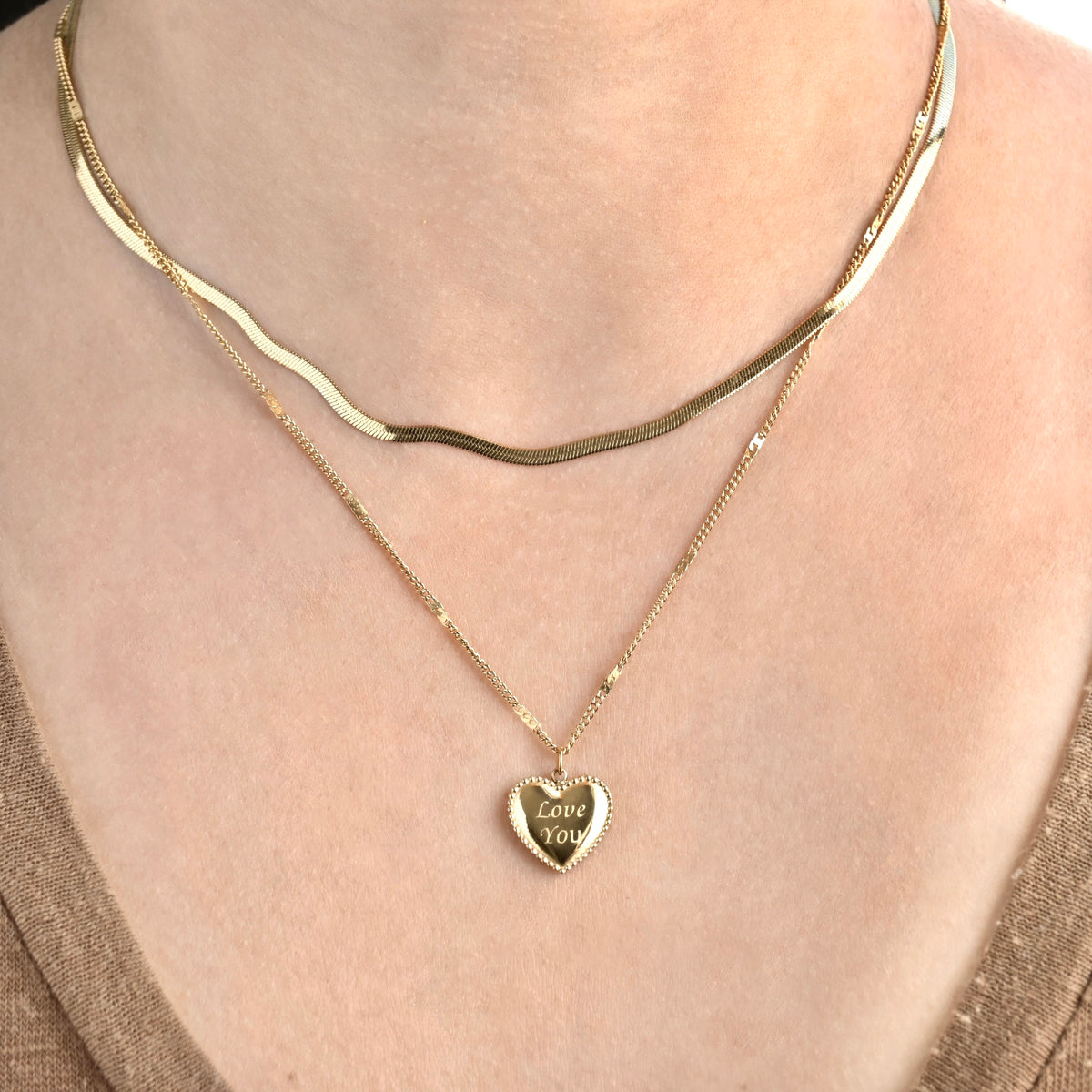 front view of the person wearing a necklace set with herringbone chain and heart pendant