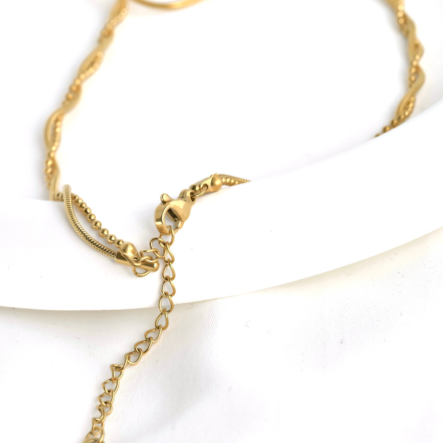 Close up of necklace's clasp area where the ball and snake chain linked together and secured with a lobster claw clasp and extender chain.