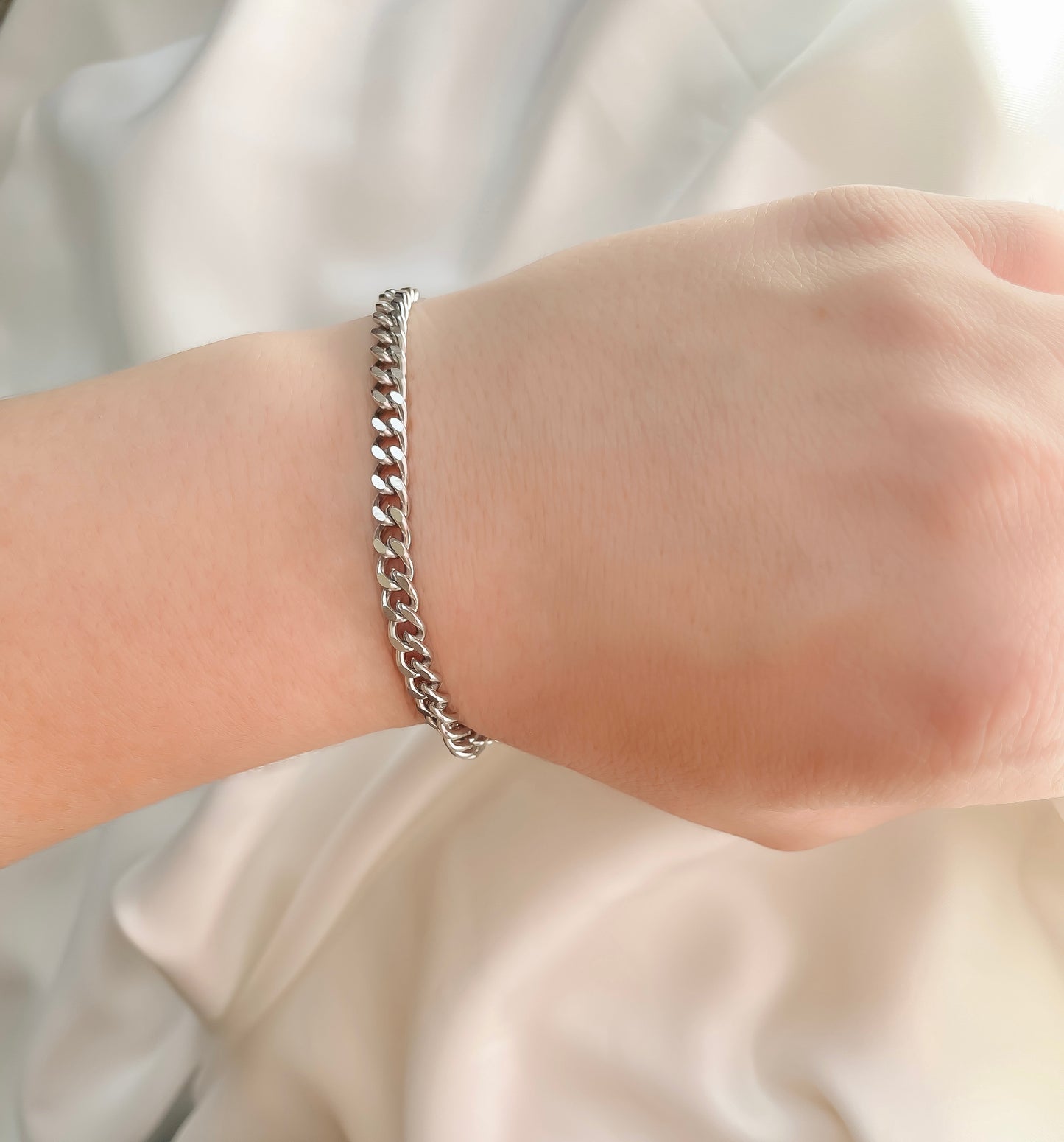 5mm silver curb link chain bracelet on a wrist with a neutral background