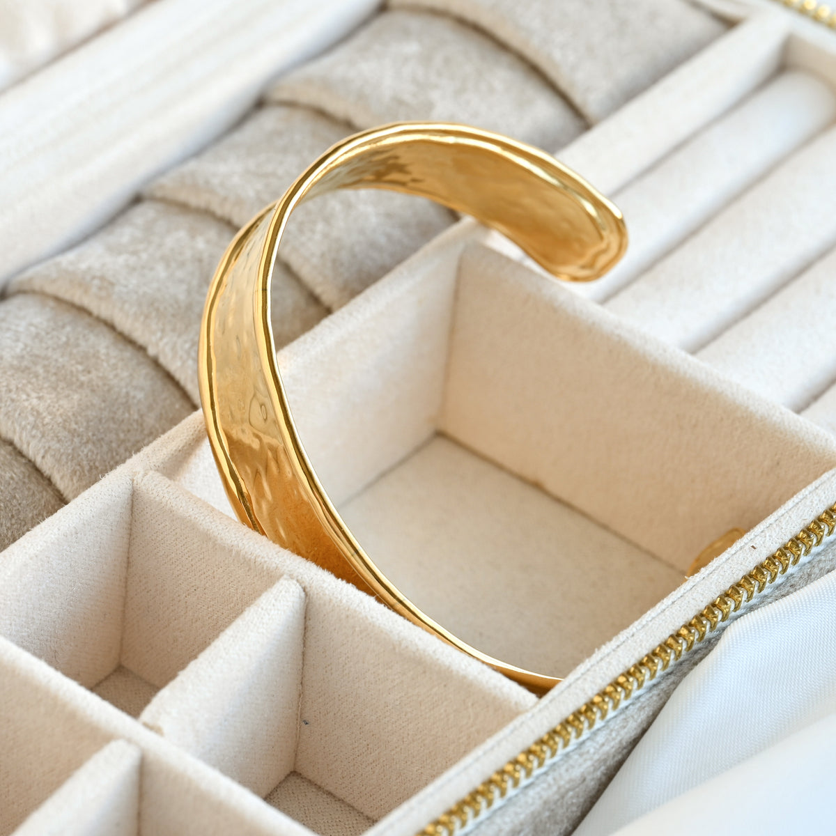 Gold cuff bracelet in a jewelry box with a beige interior