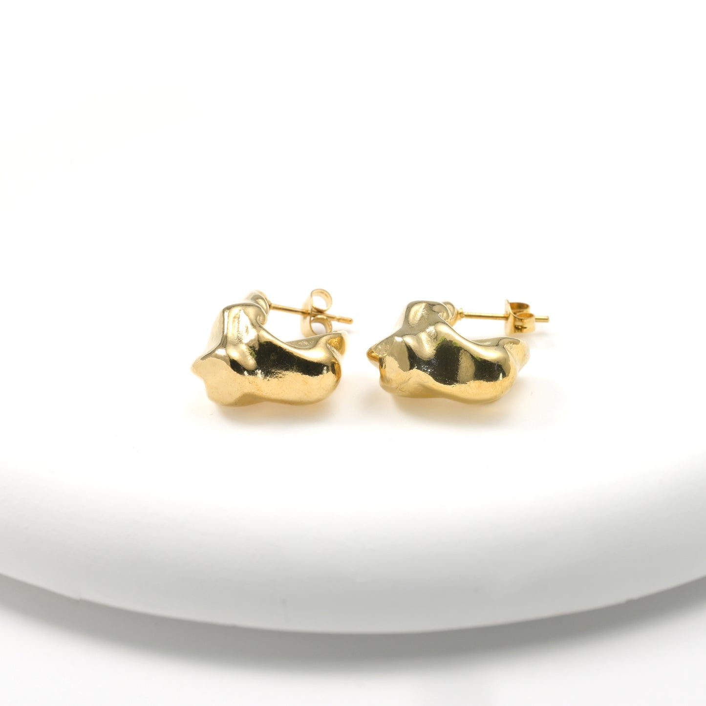 Pair of fluid gold earrings on a white background