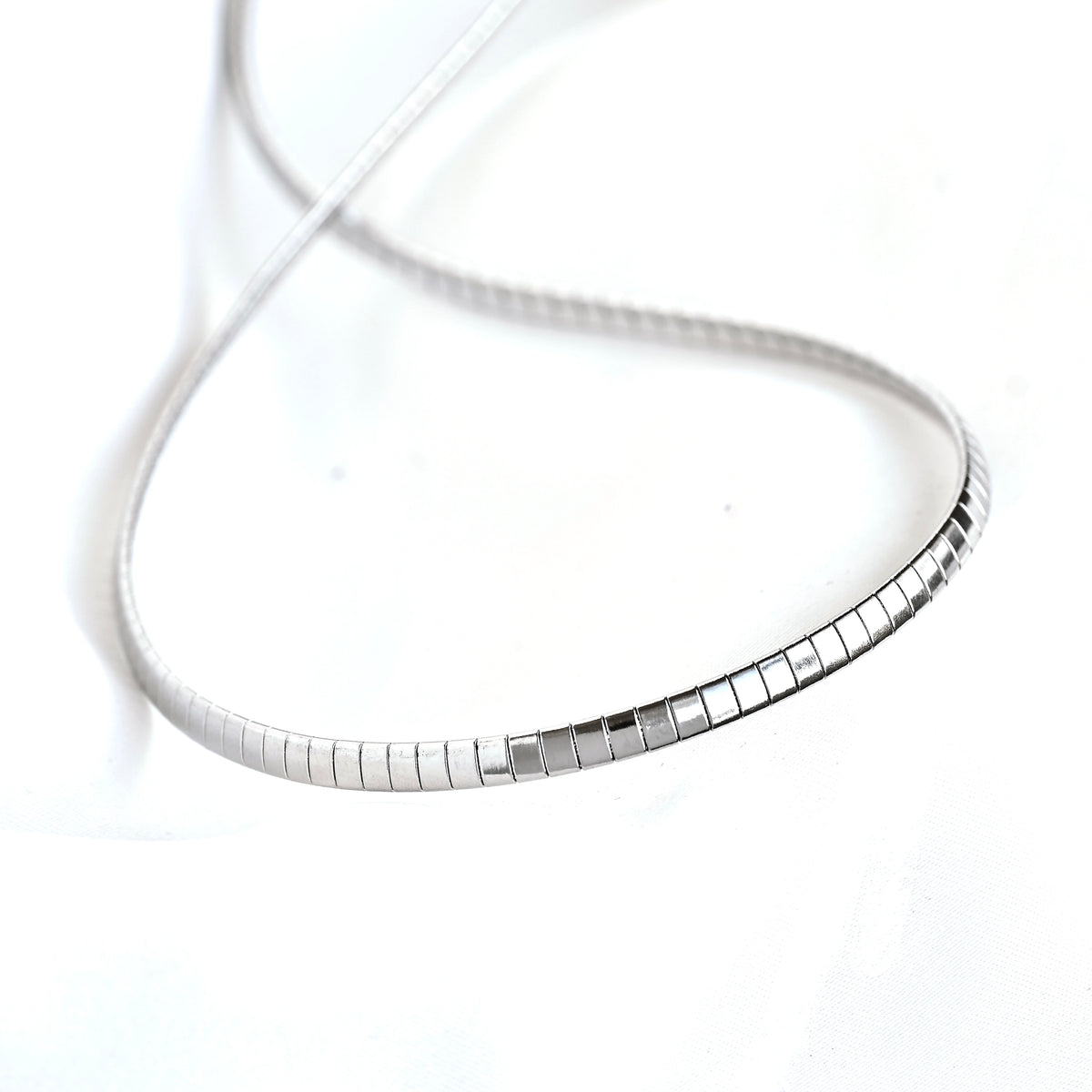 A silver snake chain necklace with a polished rectangular link accent, displayed on a clean white background.