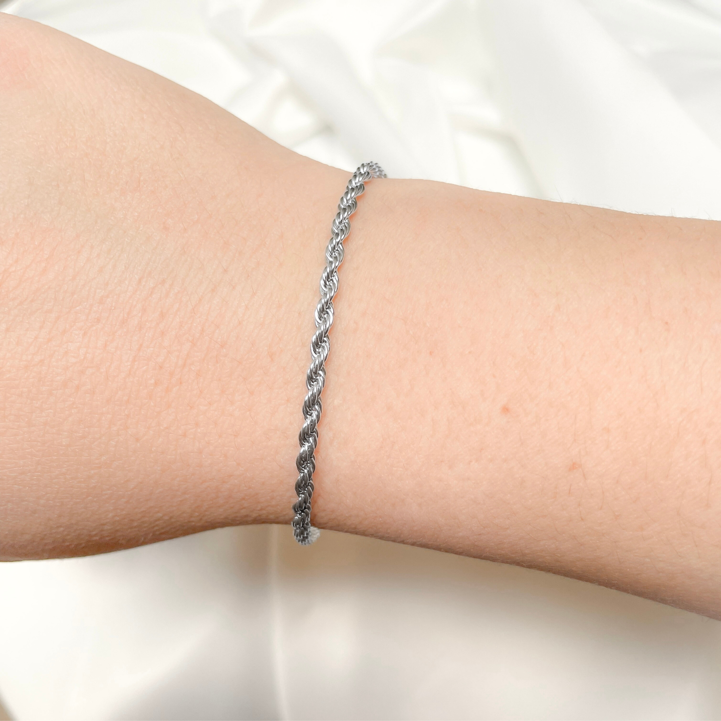 Silver braided bracelet on a wrist against a white background
