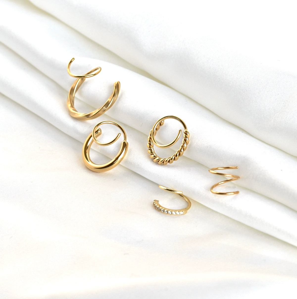 Set of gold twist earrings on a white background