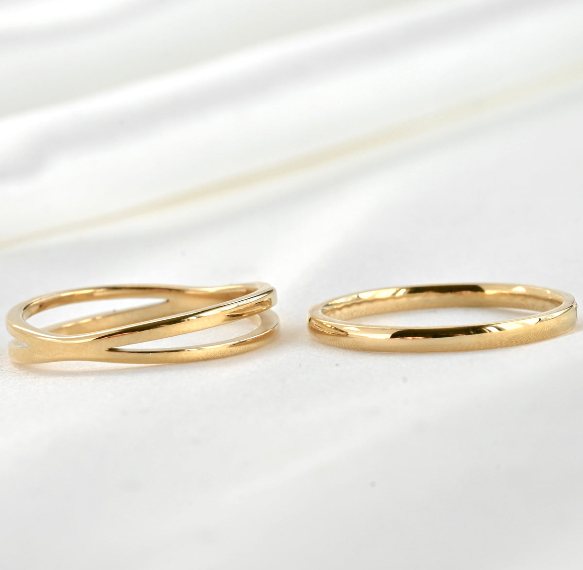 Back view of two gold rings with smooeth polished finish with no CZ on a white satin background