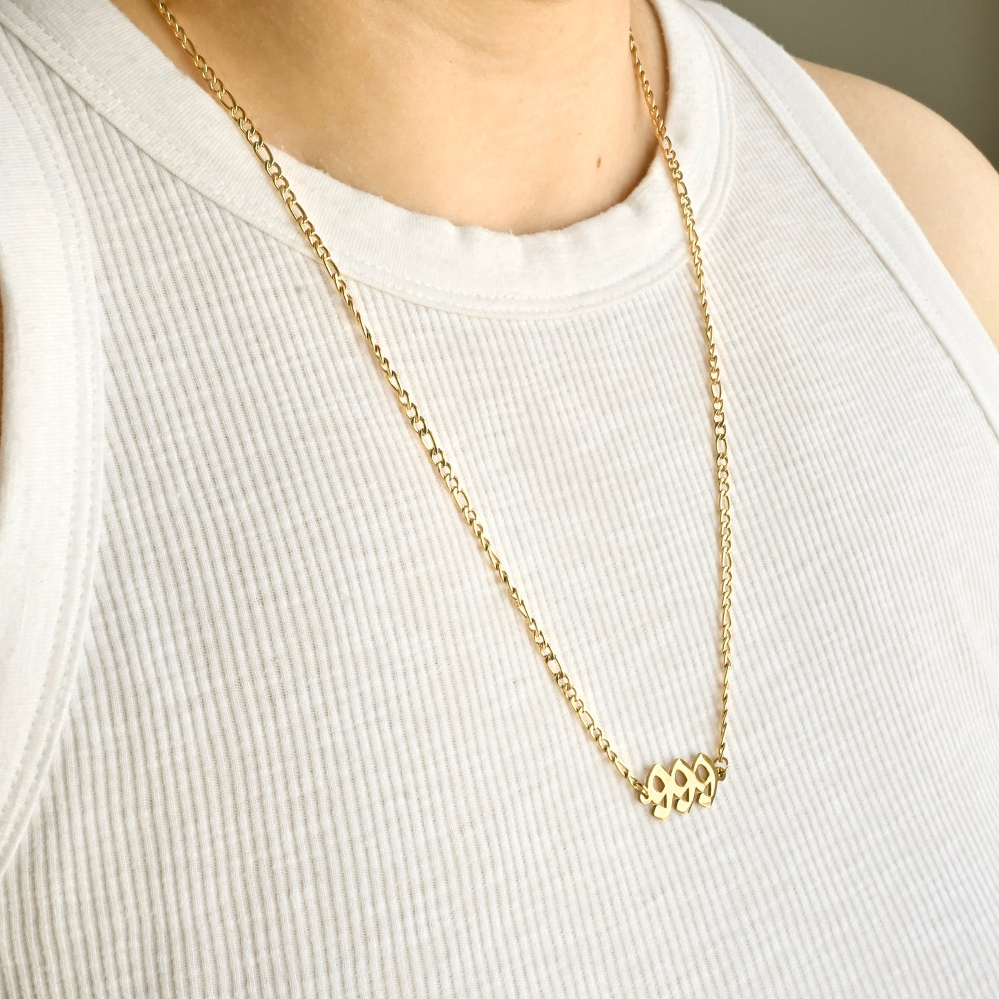 Long figaro chain necklace with a small angel number pendant on a white tank top