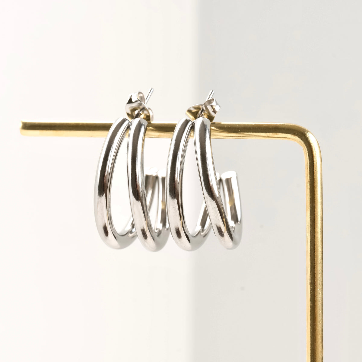 Medium Silver hoop earrings on a gold stand against a white background