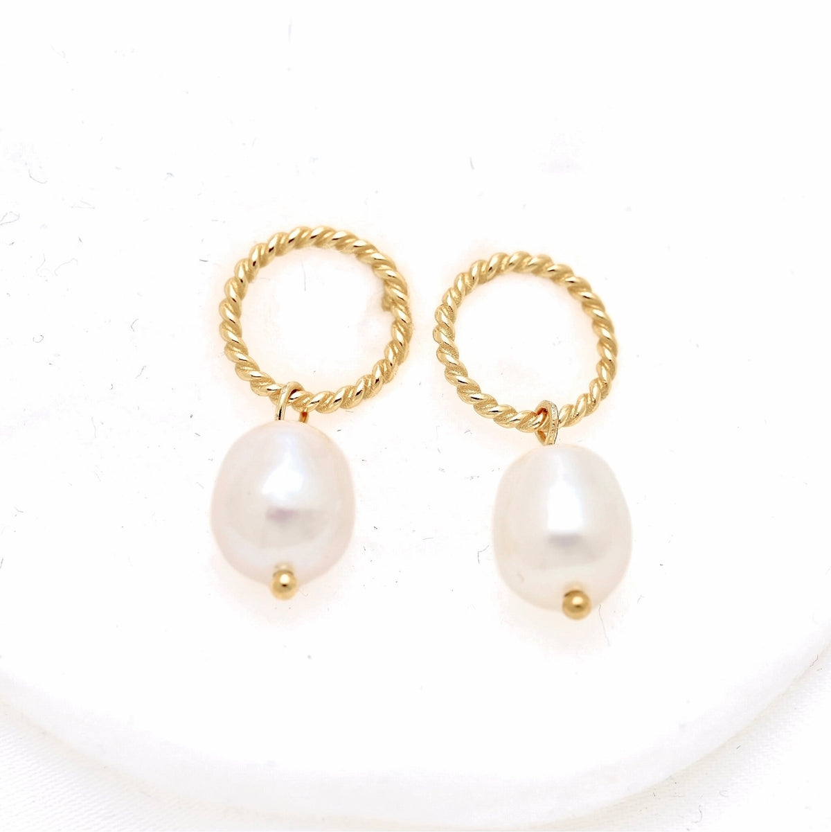 A pair of gold hoop earrings with twisted rope tops and dangling baroque pearl drops, displayed on a clean white background.