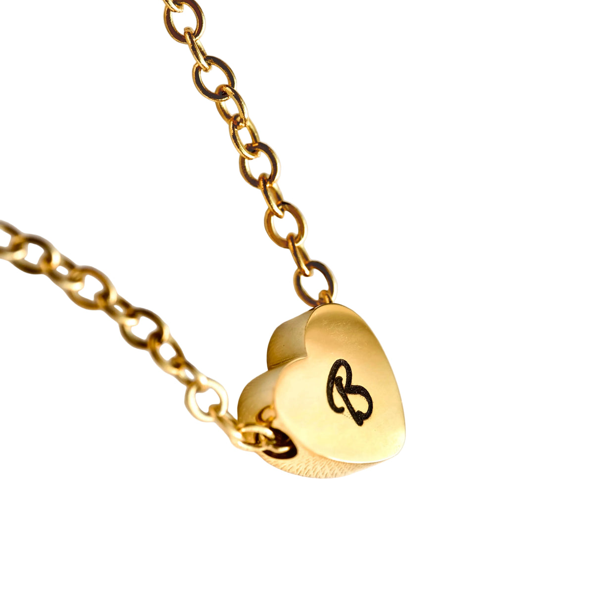 Gold necklace with an engraved heart charm on a white background