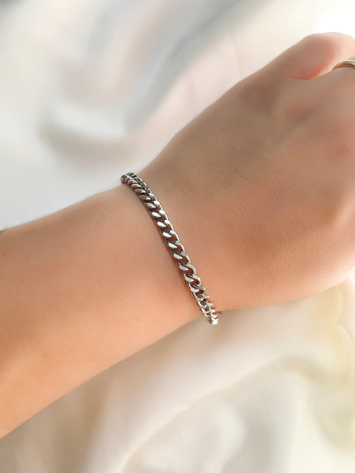 5mm Silver cuban chain bracelet reflecting light on a wrist against a neutral background