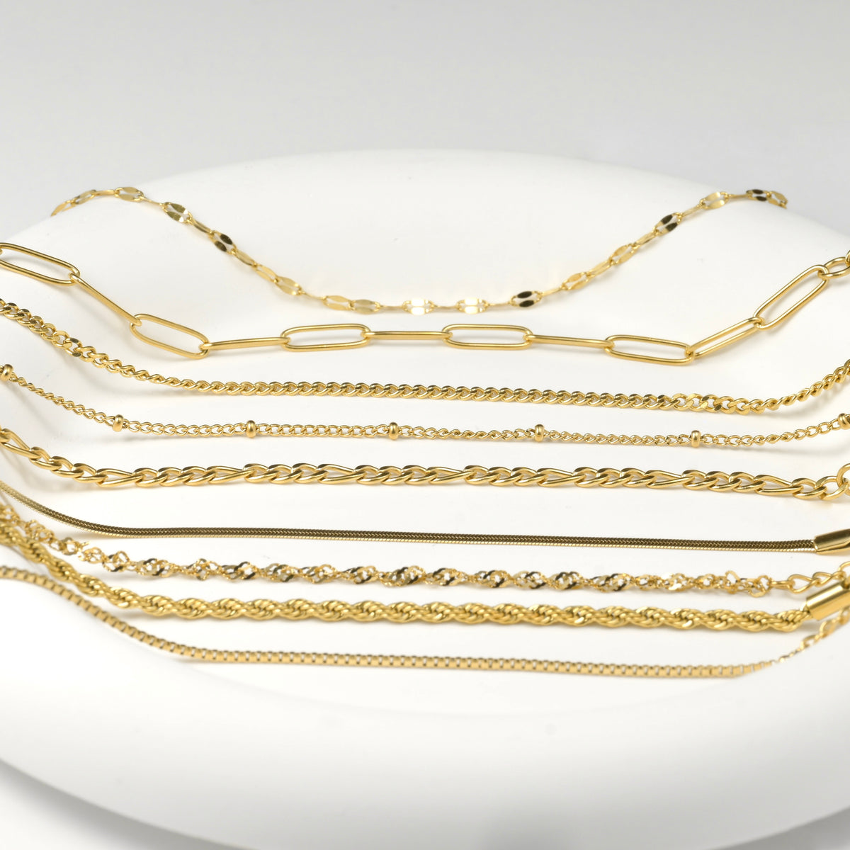 Set of gold bracelets on a white plate