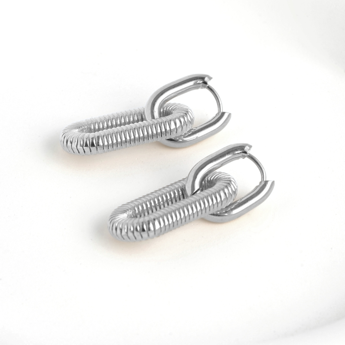 Pair of silver double link hoop earrings on a white background