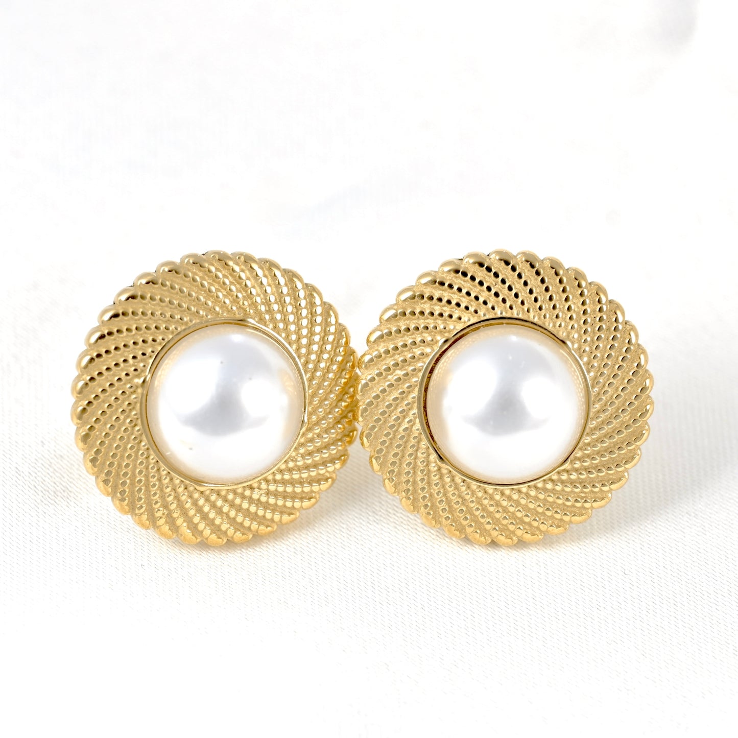Close up front view of a pair of vintage-style gold pearl earrings on white background