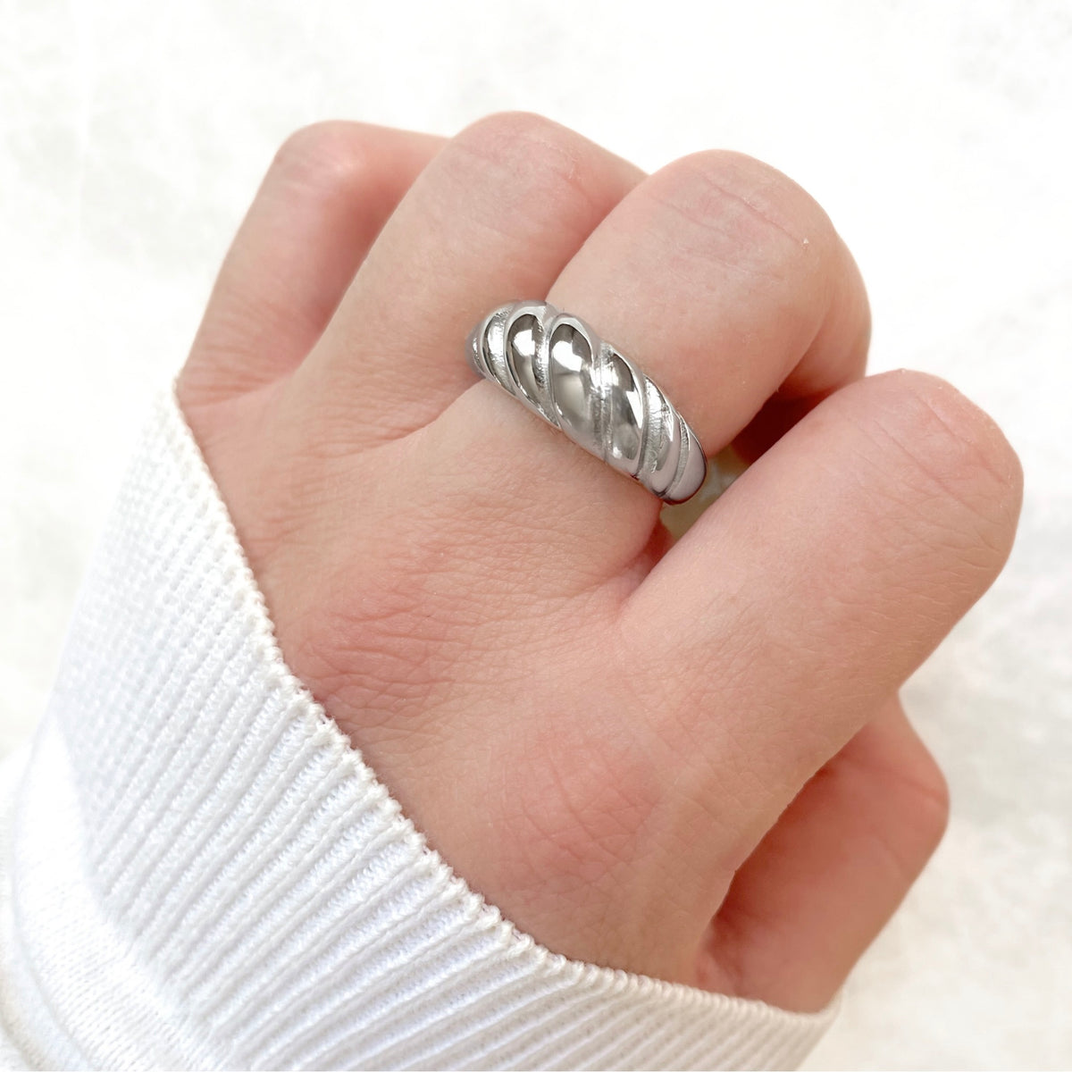 Silver braided dome ring on a person's finger with a white background