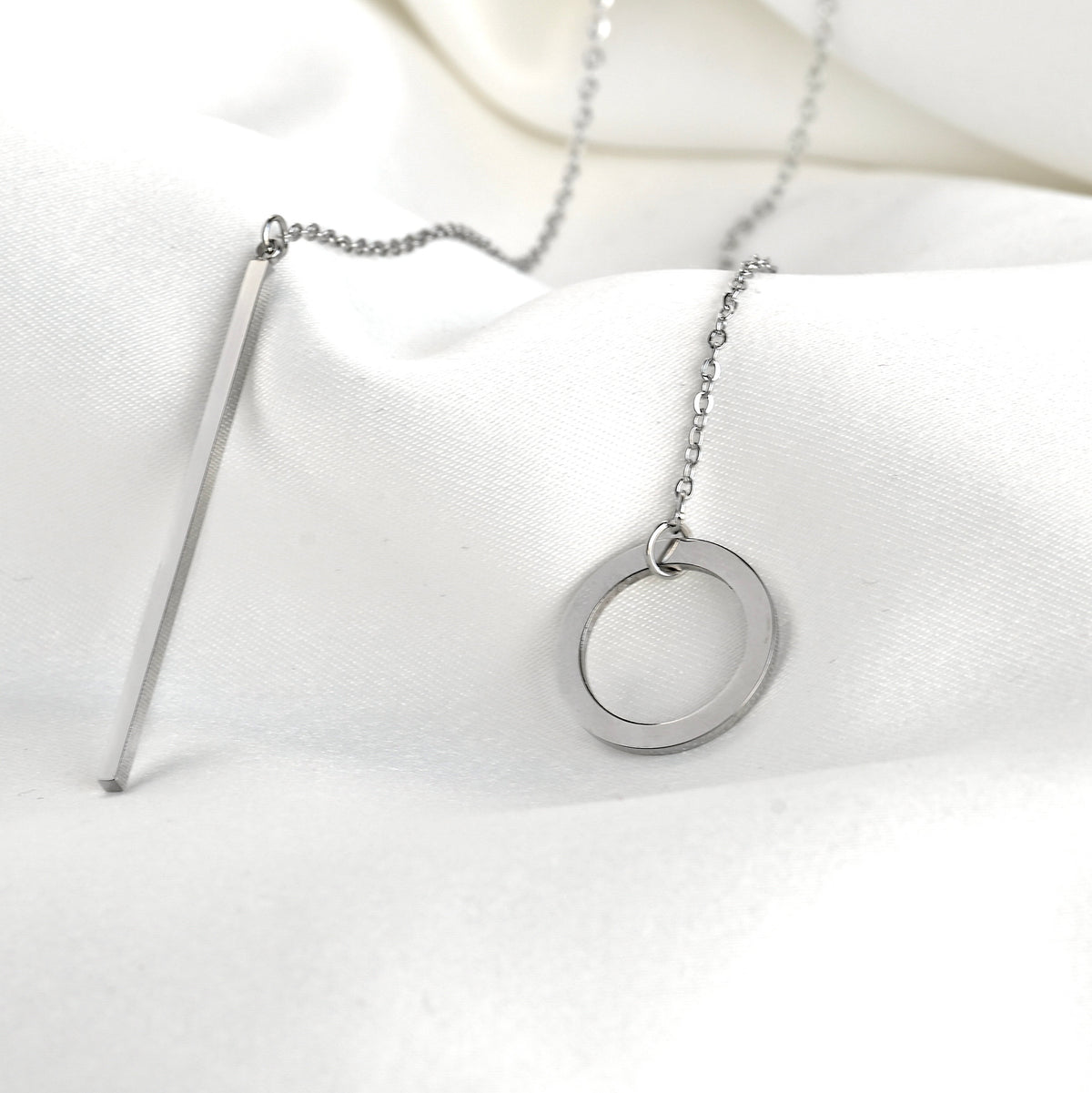 Silver necklace with a circle and bar side by side on a white background