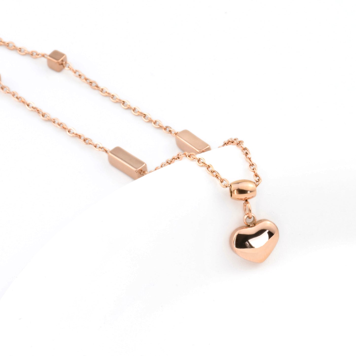 Rose gold anklet with heart pendant on a white background