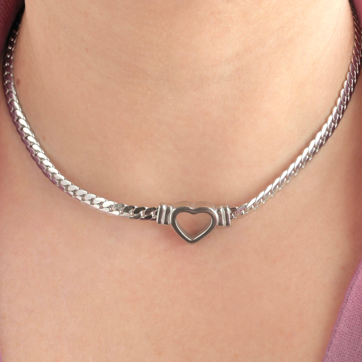 Thick silver necklace with a heart pendant on a person's neck