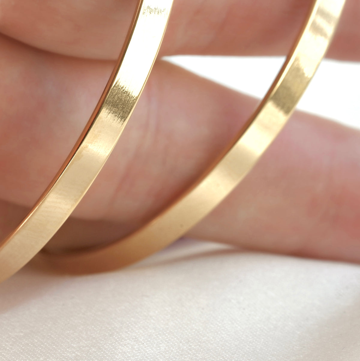 Wide gold angular edge hoops on hand