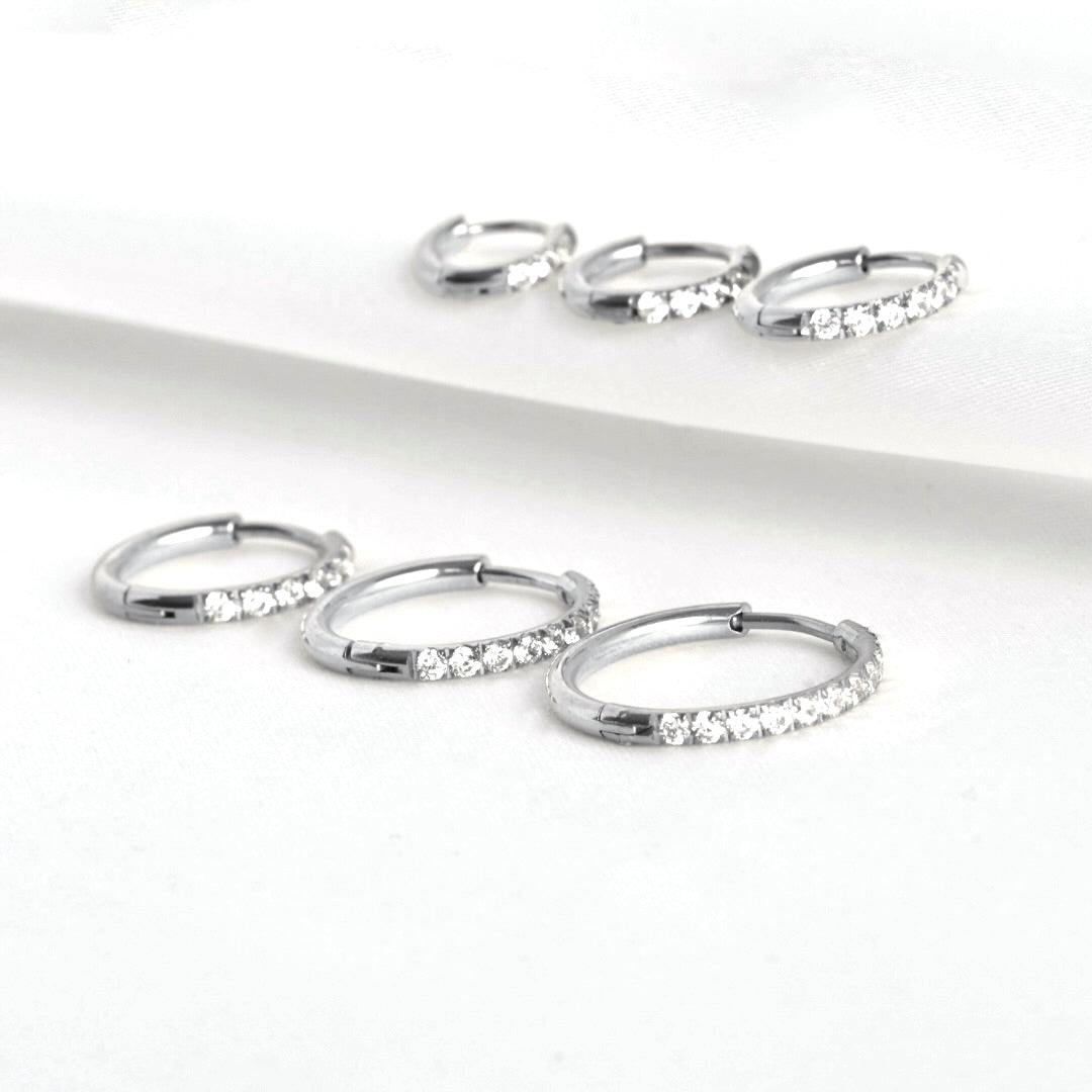 Set of silver cz hoop earrings with embedded stones on a white background