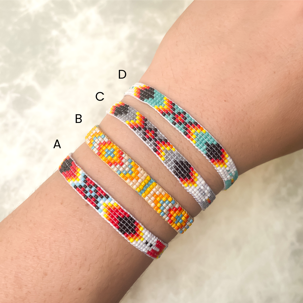 Four woven beaded bracelets on a wrist with a neutral background