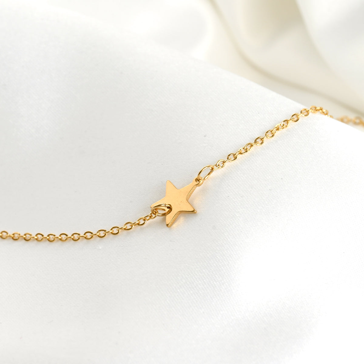 Gold necklace with a star charm on a delicate cable chain against a white background