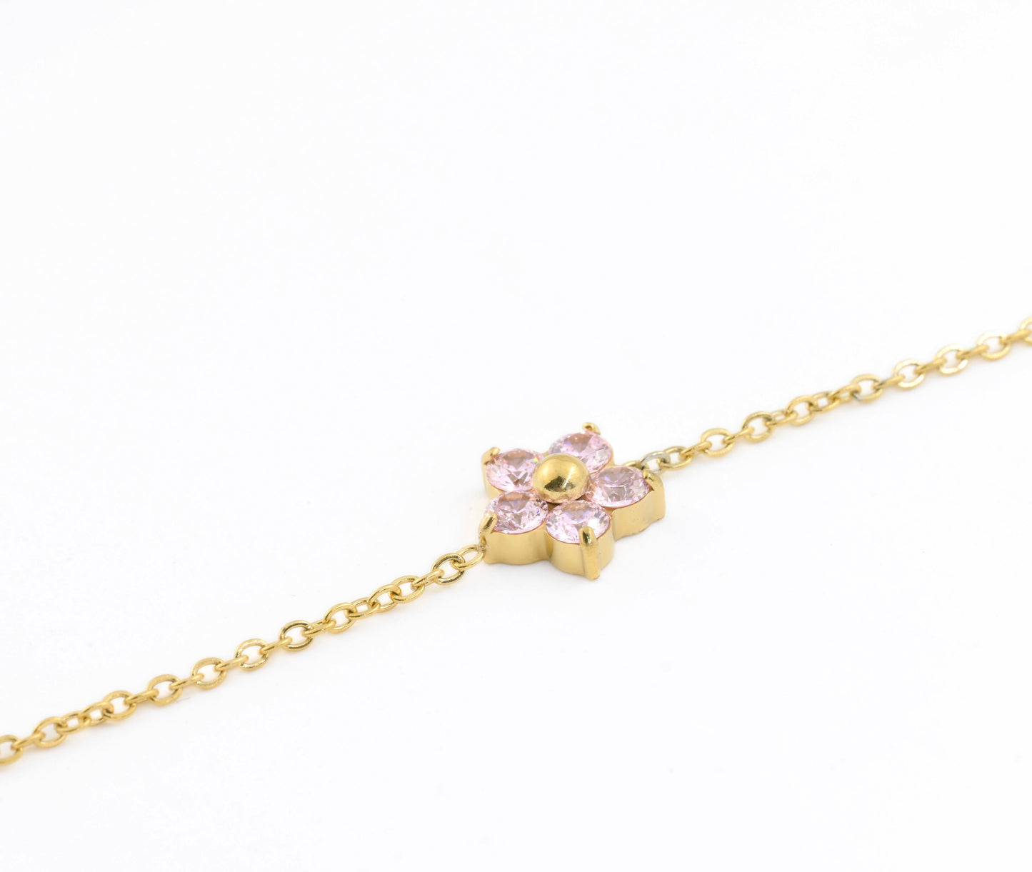 Gold bracelet with a flower charm featuring pink CZ petals on a white background
