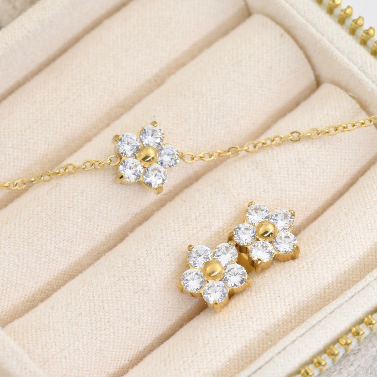 Gold cz flower bracelet abd two stud earrings on a beige jewelry box