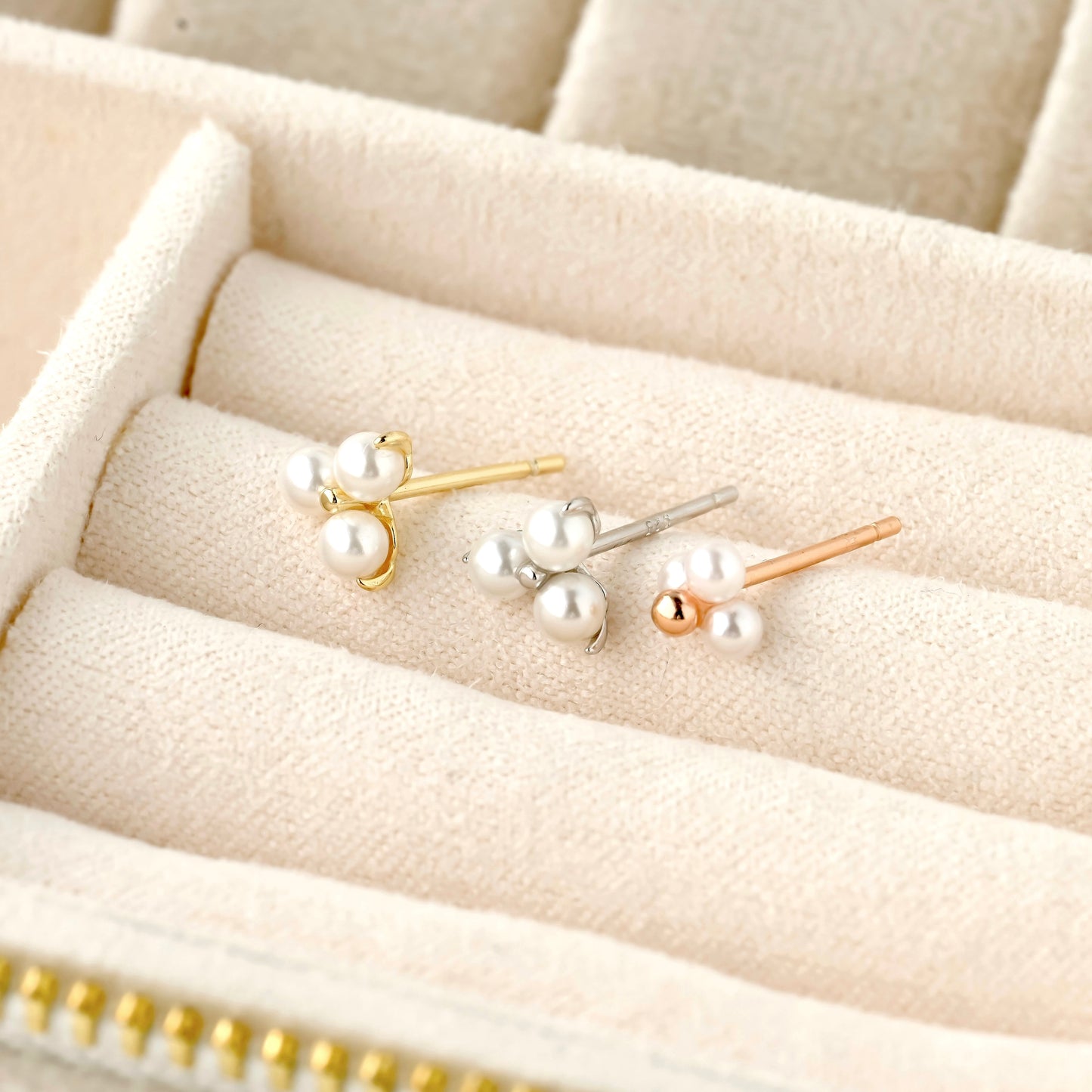 pearl stud earrings in gold, silver and rose gold on a beige jewelry box