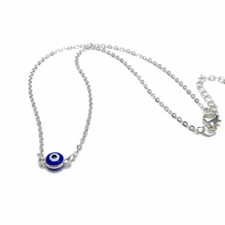 Silver necklace with a small blue evil eye bead on a white background