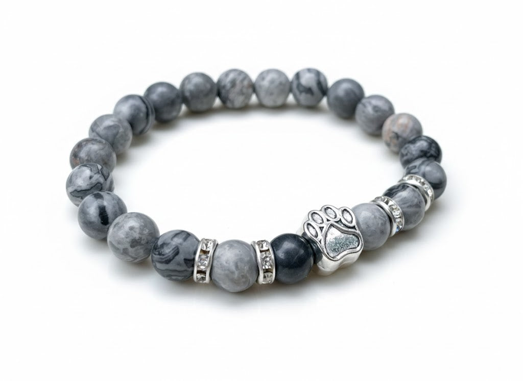 Close-up view of gray stone bracelet with a paw print charm on a white background