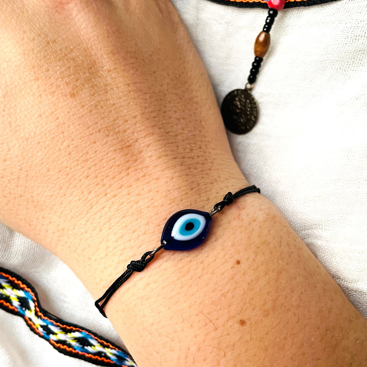 Bracelet with an eye-shaped charm on a wrist against a white background