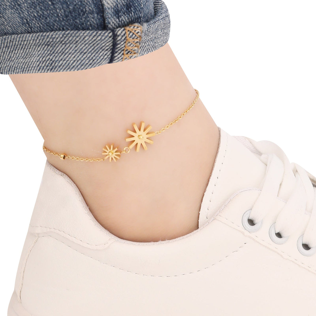 Gold ankletwith sunflower designs on a person's ankle against a white background