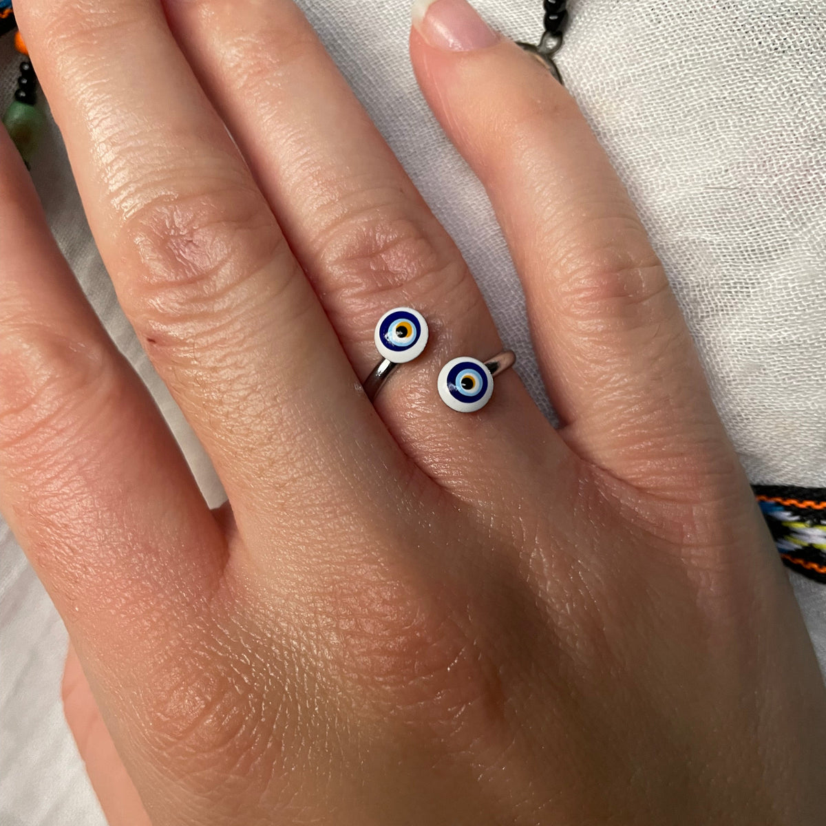 Hand wearing a ring with a blue and white design on a light background