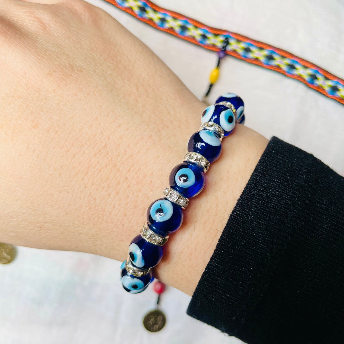 Blue beaded bracelet on a wrist with a colorful patterned strap in the background