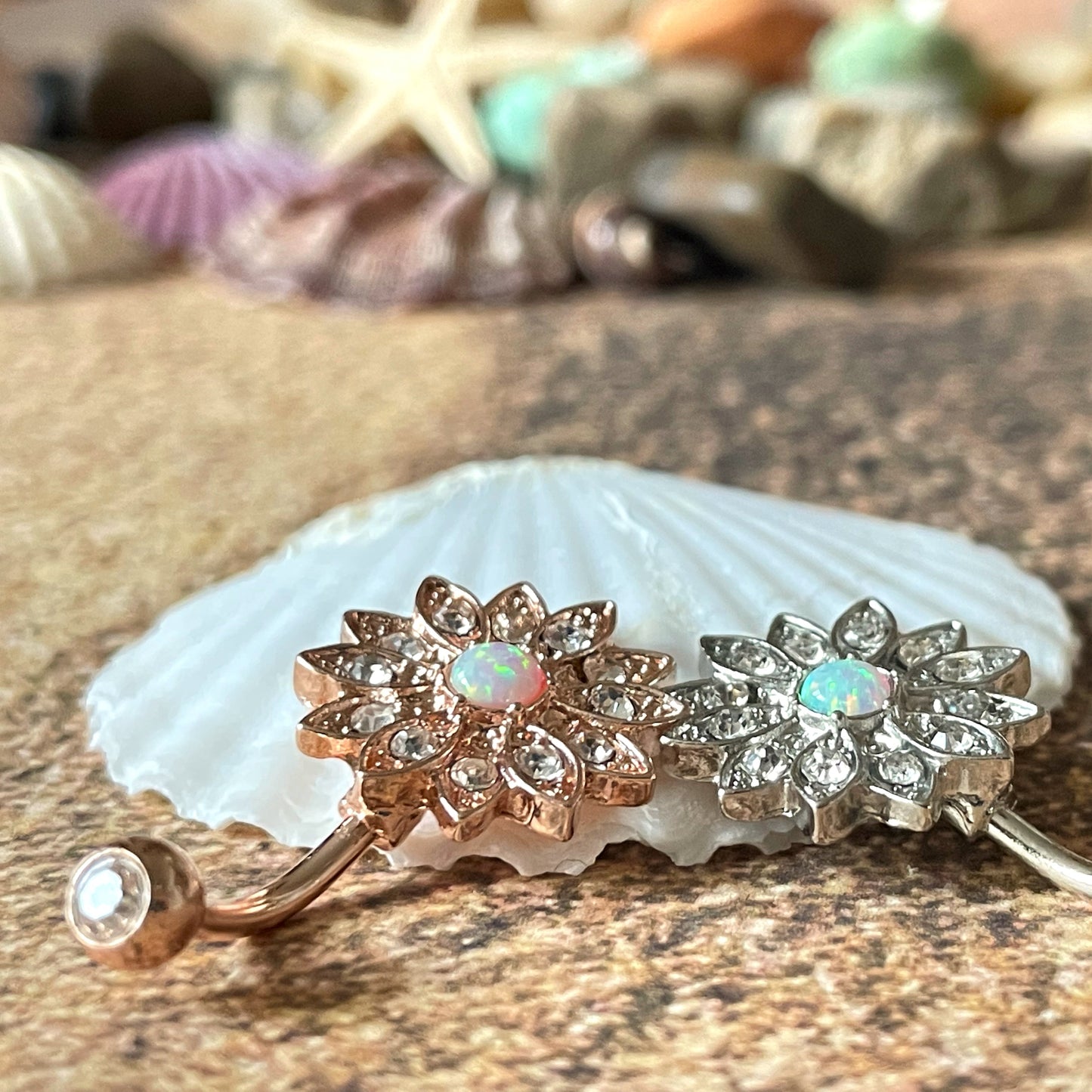 Decorative belly button ring with floral designs on a shell and stone background
