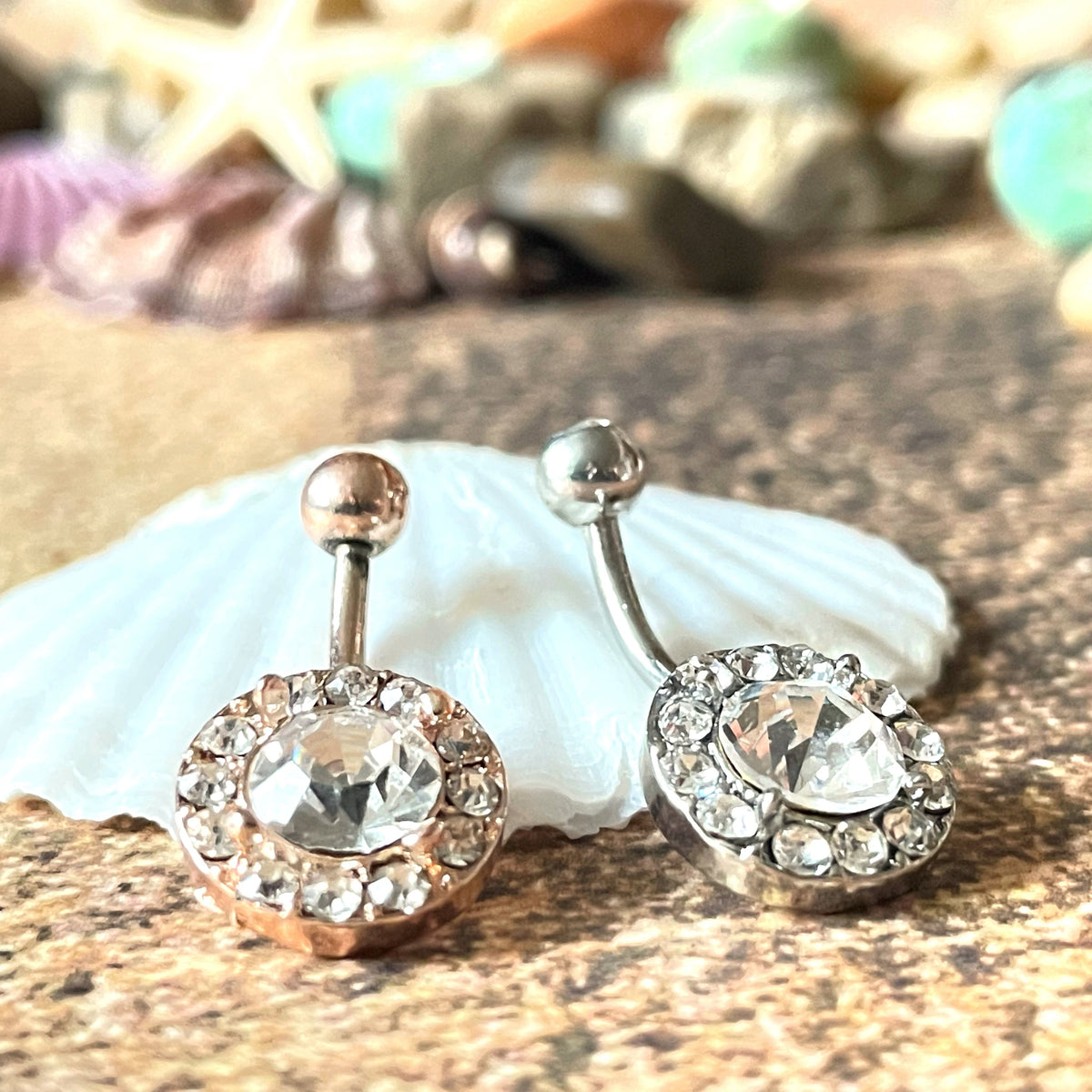 Belly rings with gemstones on a shell and stone background