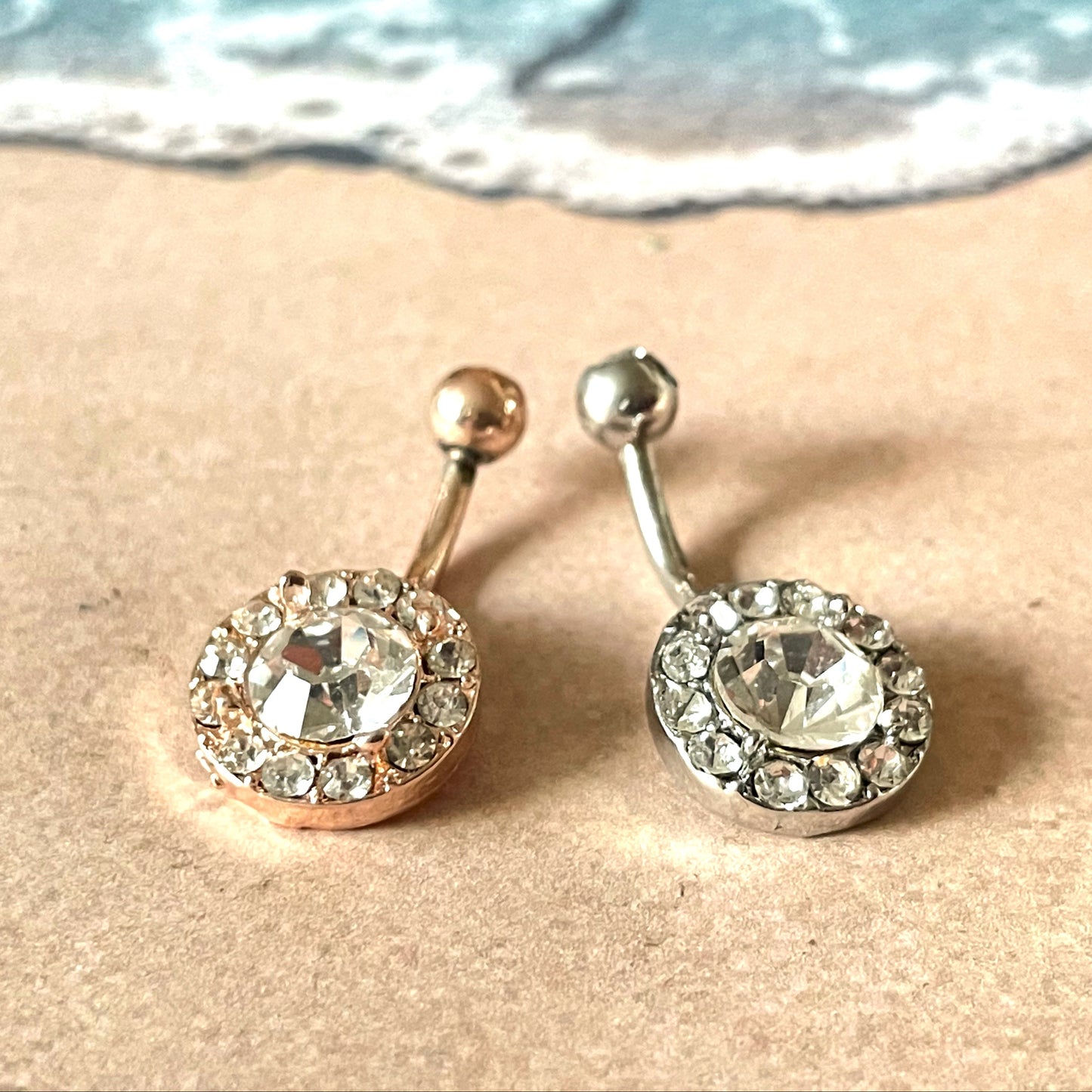 Belly button rings with gemstones on a sandy beach