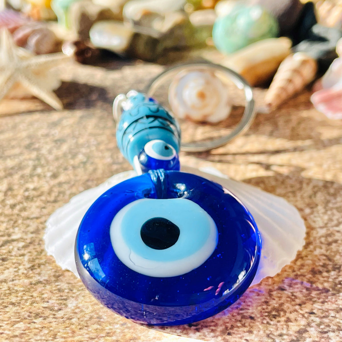 Close-up view of blue glass keychain with an evil eye design, accompanied by wooden beads in blue and silver accents.